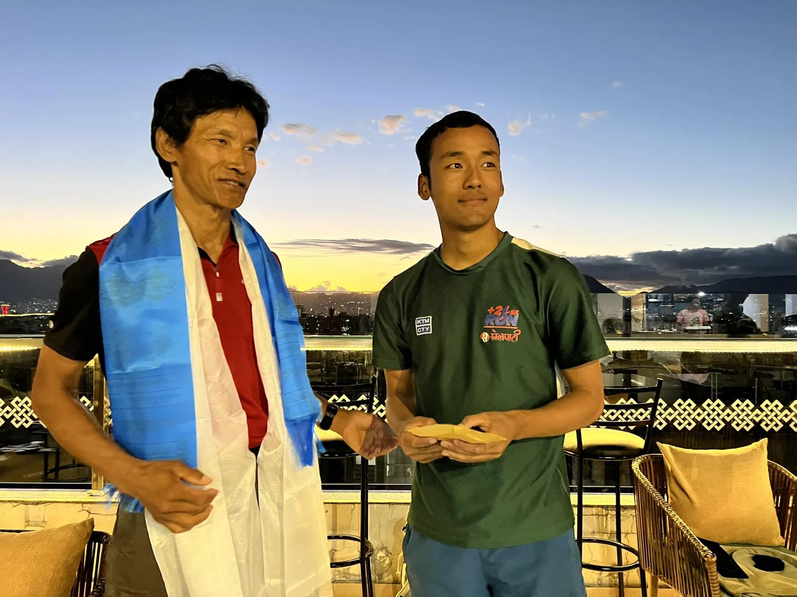 Dawa Dachhiri Sherpa remet une enveloppe à un jeune homme sur une terrasse de Kathmandu