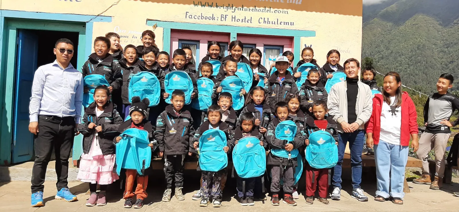 Les enfants du pensionnat de Chhulemu alignés avec leurs sacs à dos neufs devant le bâtiment