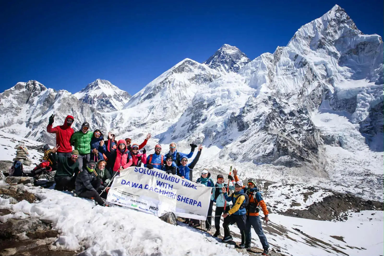 Groupe de coureurs du Solukhumbu Trail posant avec une banderole devant l'Everest enneigé